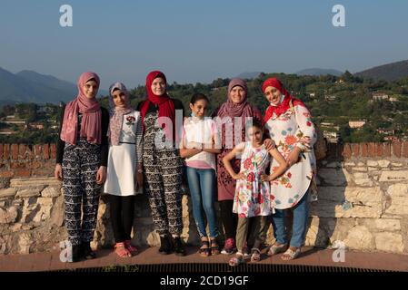 Les femmes égyptiennes posent devant la caméra sur le toit-terrasse avec vue aérienne de la vieille ville italienne de Brescia. Banque D'Images