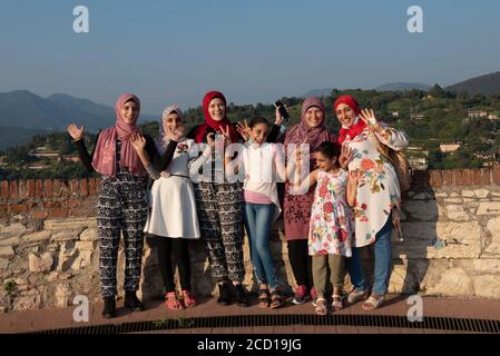 Les femmes égyptiennes posent devant la caméra sur le toit-terrasse avec vue aérienne de la vieille ville italienne de Brescia. Banque D'Images