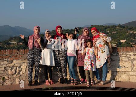 Les femmes égyptiennes posent devant la caméra sur le toit-terrasse avec vue aérienne de la vieille ville italienne de Brescia. Banque D'Images