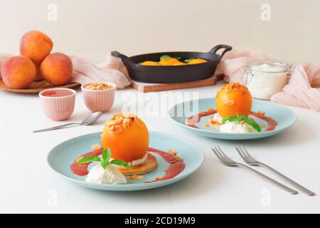 Pêches rôties avec crème fraîche au citron, citron vert et basilic et coulis de framboises. Délicieux dessert aux fruits doux, le Gordon Ramsey. Vue de dessus, woode blanc Banque D'Images