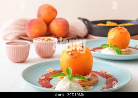 Pêches rôties avec crème fraîche au citron, citron vert et basilic et coulis de framboises. Délicieux dessert aux fruits doux, le Gordon Ramsey. Vue de dessus, woode blanc Banque D'Images