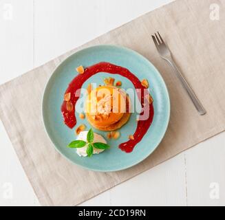 Pêches rôties avec crème fraîche au citron, citron vert et basilic et coulis de framboises. Délicieux dessert aux fruits doux, le Gordon Ramsey. Vue de dessus, woode blanc Banque D'Images