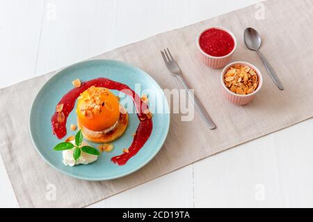 Pêches rôties avec crème fraîche au citron, citron vert et basilic et coulis de framboises. Délicieux dessert aux fruits doux, le Gordon Ramsey. Vue de dessus, woode blanc Banque D'Images