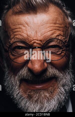 Homme mature avec une grimace en colère sur le visage révélant dans les yeux vissés, le sourire méchant et les vieux rides profondes gros plan. Émotions humaines et expres faciales Banque D'Images