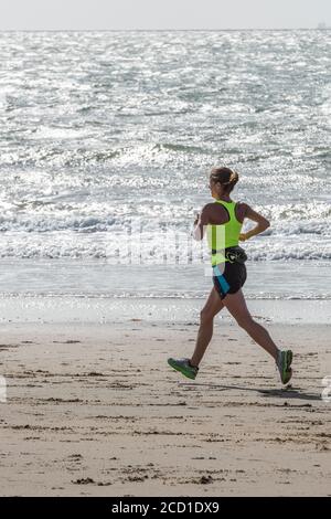une jeune femme portant des vêtements de sport pour la course à pied sur une plage sur l'île de wight Banque D'Images