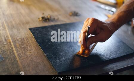 Processus de travail de l'article en cuir dans l'atelier. Homme tenant un outil de fabrication et travaillant. Artisan au travail. Banque D'Images