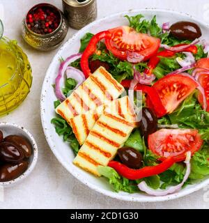 Salade délicieuse au fromage halloumi grillé, laitue, tomates, poivrons, oignons rouges, olives Kalamata, huile d'olive, épices. Cuisine méditerranéenne. Banque D'Images
