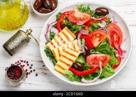 Salade délicieuse au fromage halloumi grillé, laitue, tomates, poivrons, oignons rouges, olives Kalamata, huile d'olive, épices. Cuisine méditerranéenne. Banque D'Images