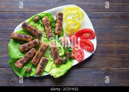 Cuisine des Balkans. Cevavi - plat grillé de viande hachée sur une table rustique. Flat lay, espace de copie Banque D'Images