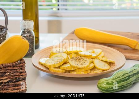Tranches de courgettes sur une assiette. Gros plan de tranches de courgettes fraîches et biologiques, avec du poivre noir et du sel d'assaisonnement, prêtes à être cuites Banque D'Images