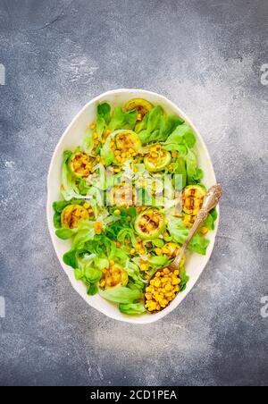 Délicieuse salade de laitue fraîche avec courgettes grillées, maïs et fromage de chèvre doux aux épices et à l'huile d'olive. Mise au point sélective, vue de dessus Banque D'Images