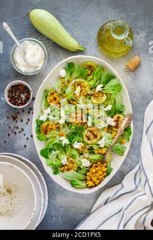 Délicieuse salade de laitue fraîche avec courgettes grillées, maïs et fromage de chèvre doux aux épices et à l'huile d'olive. Mise au point sélective, vue de dessus Banque D'Images