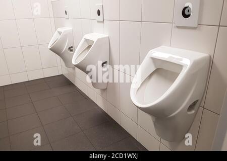 Rangée d'urinoirs dans les toilettes publiques Banque D'Images