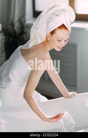 Routine matinale de beauté rouge dans la salle de bains. Femme courant bain, veut se rafraîchir dans l'eau. Banque D'Images