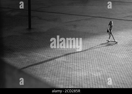 Femme sur un skateboard dans la ville. Belle photo noire et blanche contrastée d'une femme qui fait le tour de la ville. Banque D'Images