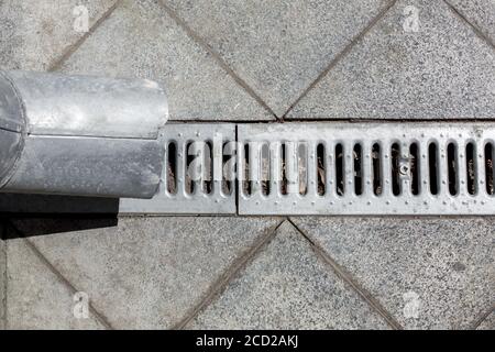 une structure d'ingénierie un tuyau de vidange avec une grille de drainage pour drainage de l'eau de pluie sur un fond de granit de pierre trottoir de carreaux carrés Banque D'Images