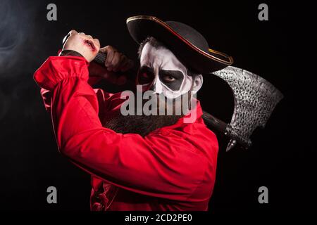 Homme habillé comme un pirate pour halloween tenue et hache sur fond noir. Banque D'Images