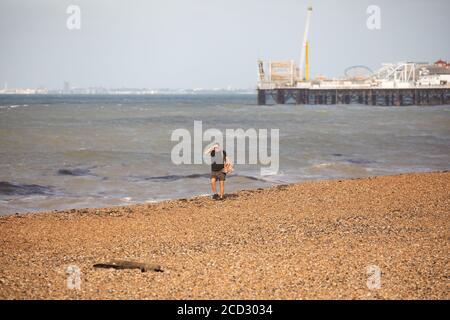 Brighton, Royaume-Uni. 26 août 2020. Un homme marche le long du front de mer à Brighton dans des vents forts qui sont des vestiges de Storm Francis hier. La température est de 19C avec des vents forts. La mer était également encore en train de franchir le mur du port de plaisance. Crédit : Keith Larby/Alay Live News Banque D'Images