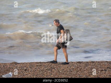 Brighton, Royaume-Uni. 26 août 2020. Un homme marche le long du front de mer à Brighton dans des vents forts qui sont des vestiges de Storm Francis hier. La température est de 19C avec des vents forts. La mer était également encore en train de franchir le mur du port de plaisance. Crédit : Keith Larby/Alay Live News Banque D'Images