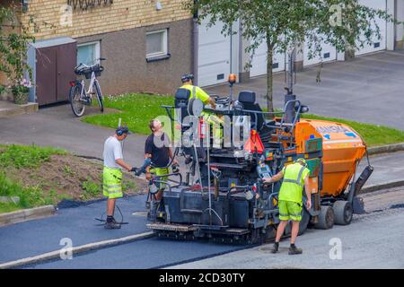 Machine de pose de béton asphaltique en opération avec les travailleurs Banque D'Images