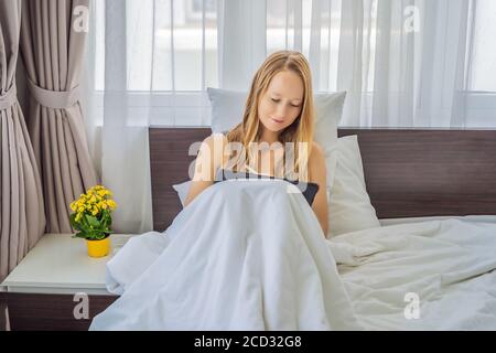 Femme tire sur une tablette avec un stylet dans le lit Banque D'Images