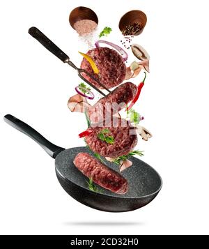 Morceaux de viande hachée de hamburger fraisés à l'état brut volant, avec ingrédients pour la cuisson. Mouvement de gel du personnel de cuisson et de la poêle. Concept de préparation alimentaire à basse teneur en GRA Banque D'Images