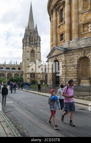 Les gens passent devant le bâtiment de la caméra Radcliffe de l'université d'Oxford et l'église de l'université de Sainte-Marie-la-Vierge, Oxford, Angleterre, Royaume-Uni. Banque D'Images