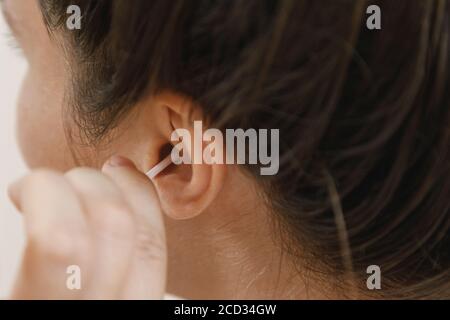 Une femme nettoie son oreille avec un coton-tige Banque D'Images