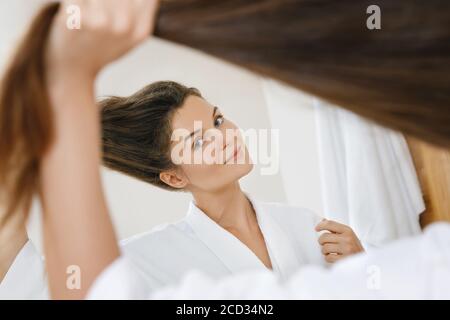 Jeune femme avec un beau cheveux fort regardant dans le miroir Banque D'Images