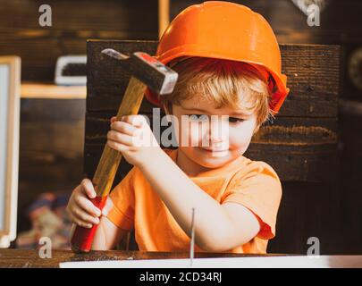 Un petit garçon avec un marteau fait des réparations. L'enfant participe activement au processus fait à la main. Banque D'Images