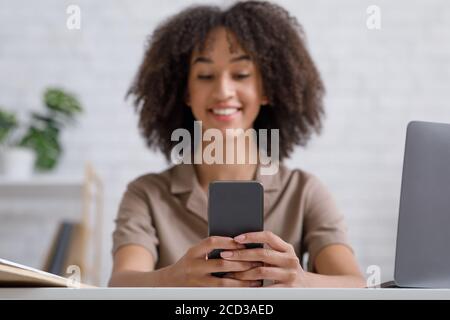 Blogueur moderne travaille de la maison pendant la quarantaine. Portrait d'une femme, utilisez un smartphone et un ordinateur portable pour discuter avec vos abonnés Banque D'Images