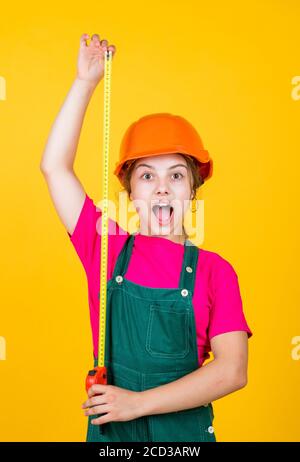 Mignon enfant en tant que travailleur de la construction. Enfant répare la maison. Enfance heureuse. Mètre-ruban en métal auto-rétractable. Petite fille utilisant un mètre ruban. Travailleur de construction avec mètre ruban. Banque D'Images