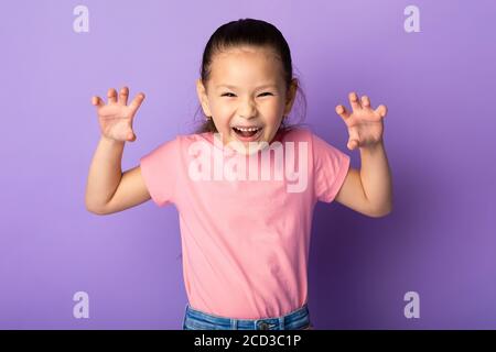 Fille asiatique grimaquant et imitant tigre, rugissant en studio Banque D'Images