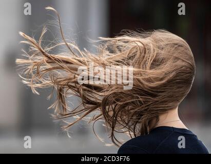 26 août 2020, Hessen, Francfort-sur-le-main : Stormy 'Kirsten' fait sauter les cheveux de cette femme dans son visage alors qu'elle se rend dans le centre-ville. Surtout entre les tours de banque, les rafales de vent gagnent en force supplémentaire. Photo : Boris Roessler/dpa Banque D'Images