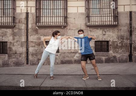 Le nouveau style normal et de message d'accueil. L'homme et la femme qui secouent les coudes ou les pieds en gardant la distance sociale pour éviter la propagation du coronavirus. Éclosion de la COVID-19 et d Banque D'Images