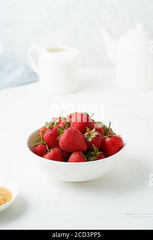 Fraises dans un bol blanc, sur une table blanche, petit déjeuner du matin, repas d'été Banque D'Images