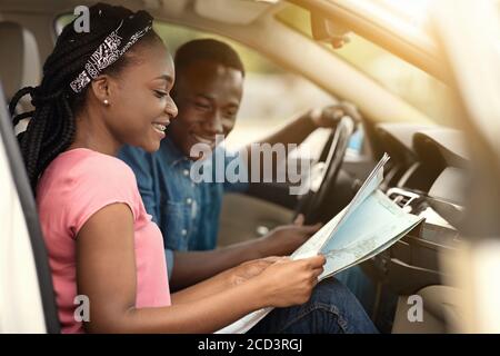 Homme et femme africains en voiture regardant la carte Banque D'Images