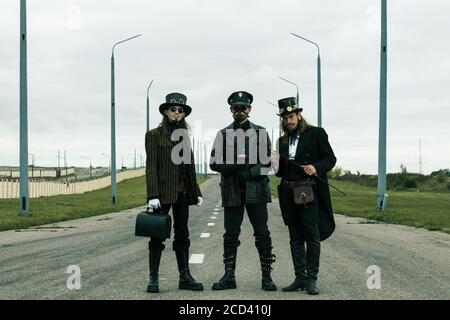 Trois personnes dans le style steampunk posant sur la route Banque D'Images