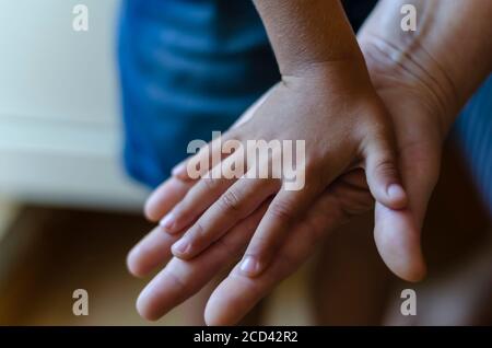 La main d'un enfant repose sur la paume d'un adulte. La paume d'un petit enfant couvre une paume ouverte pour adulte. Gros plan. Mise au point sélective. Banque D'Images