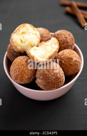 Trous de beignets faits maison dans un bol rose sur fond noir, vue latérale. Banque D'Images