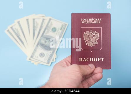 Passeport international russe dans la main de l'homme. Dollars. Arrière-plan bleu Banque D'Images