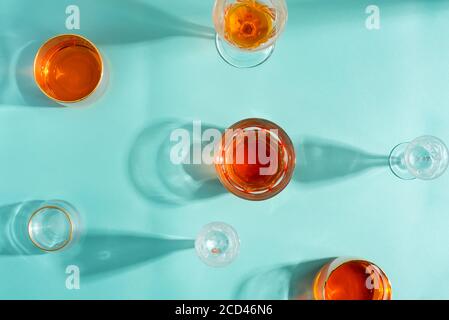 Vue de dessus de verres de vin transparents vides et remplis de boisson alcoolisée sur un fond turquoise pastel, ombres douces et longues réflexions, copie de la flèche Banque D'Images