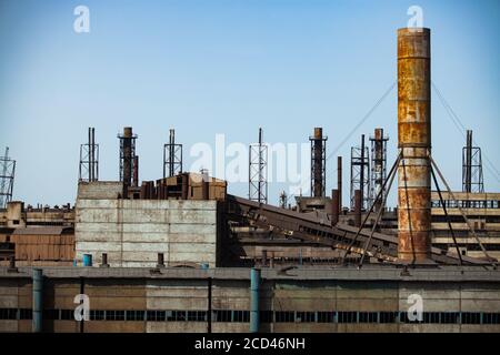 Abandon des bâtiments de l'usine métallurgique soviétique et des cheminées rouillées sur le ciel bleu. Fragment de fond industriel abstrait. Ville de Taraz. Banque D'Images