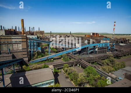 Bâtiments d'usine métallurgique abandonnés avec convoyeur bleu et cheminées rouillées sur le ciel bleu. Vue panoramique. Ville de Taraz. Banque D'Images