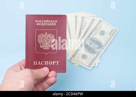 Passeport international russe dans la main de l'homme. Dollars. Arrière-plan bleu Banque D'Images