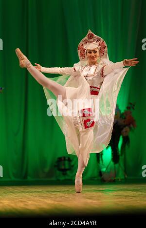 Jeune femme ballerine dans un costume blanc avec une couronne sur sa tête se produit avec une performance sur scène dans un théâtre Banque D'Images