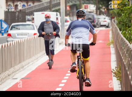 Cycliste et scooter électrique sur une piste cyclable séparée de la circulation. Espagne Banque D'Images