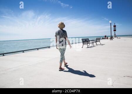 Une femme se promenant sur le mur de la mer à Bayfield, en Ontario. Banque D'Images