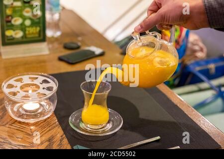 la main de l'homme verse le thé de plage de mer de la théière en verre dans une tasse de verre. gros plan, mise au point douce, arrière-plan flou. Banque D'Images