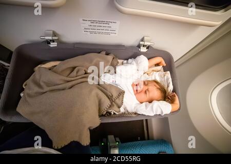 le bébé passager tout-petit se réveille dans l'avion et s'étire dans un berceau spécial pour bébé Banque D'Images